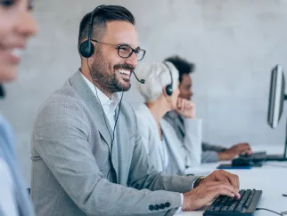 a man wearing headphones and smiling at a computer