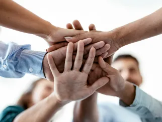 Team Hände aufeinander, von unten fotografiert