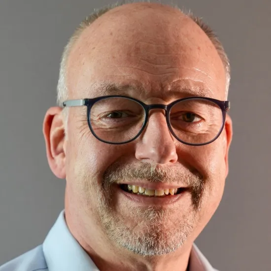 Ein Mann mit Brille und lächelnd